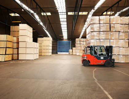 A large warehouse storing big boxes with a forklift.